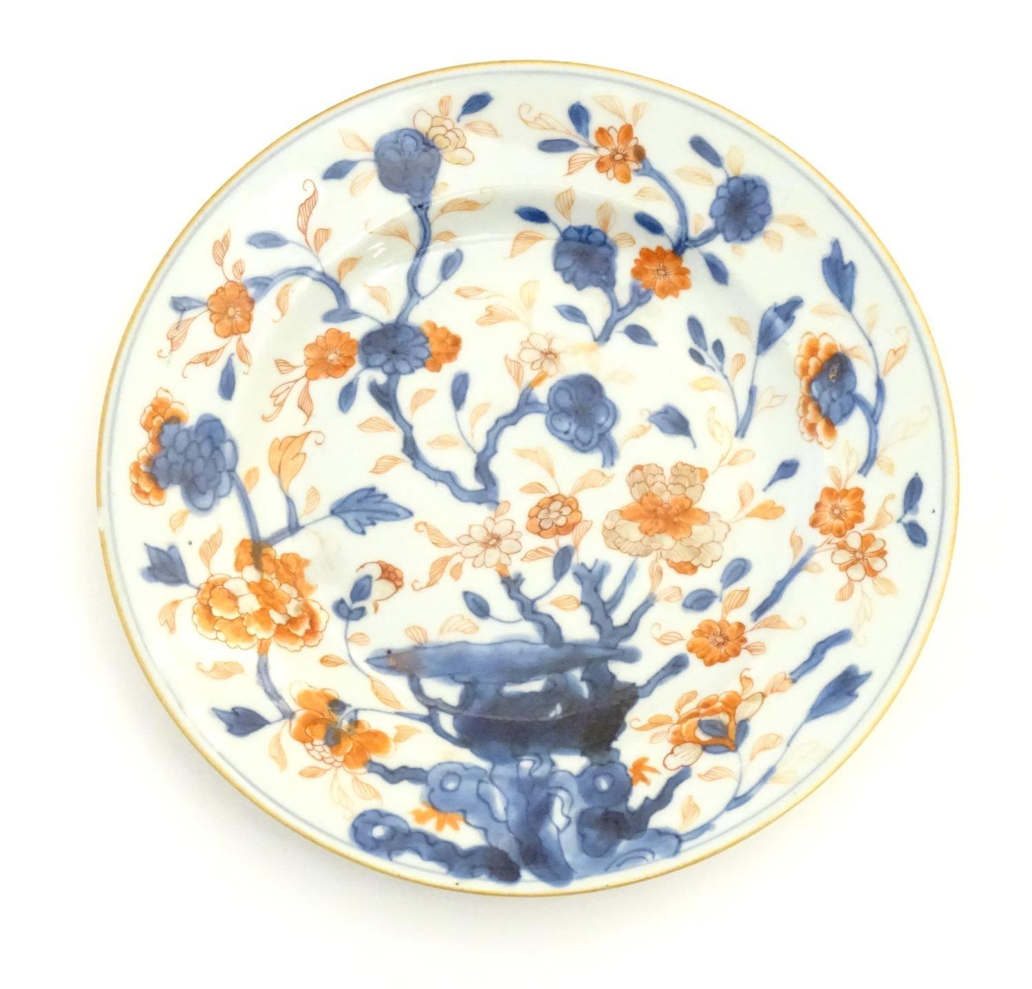 A Japanese plate in the Imari palette with hand painted decoration depicting blossoming flowers.