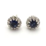 A pair of 9ct white gold stud earrings set with central blue spinel bordered by white stones in a