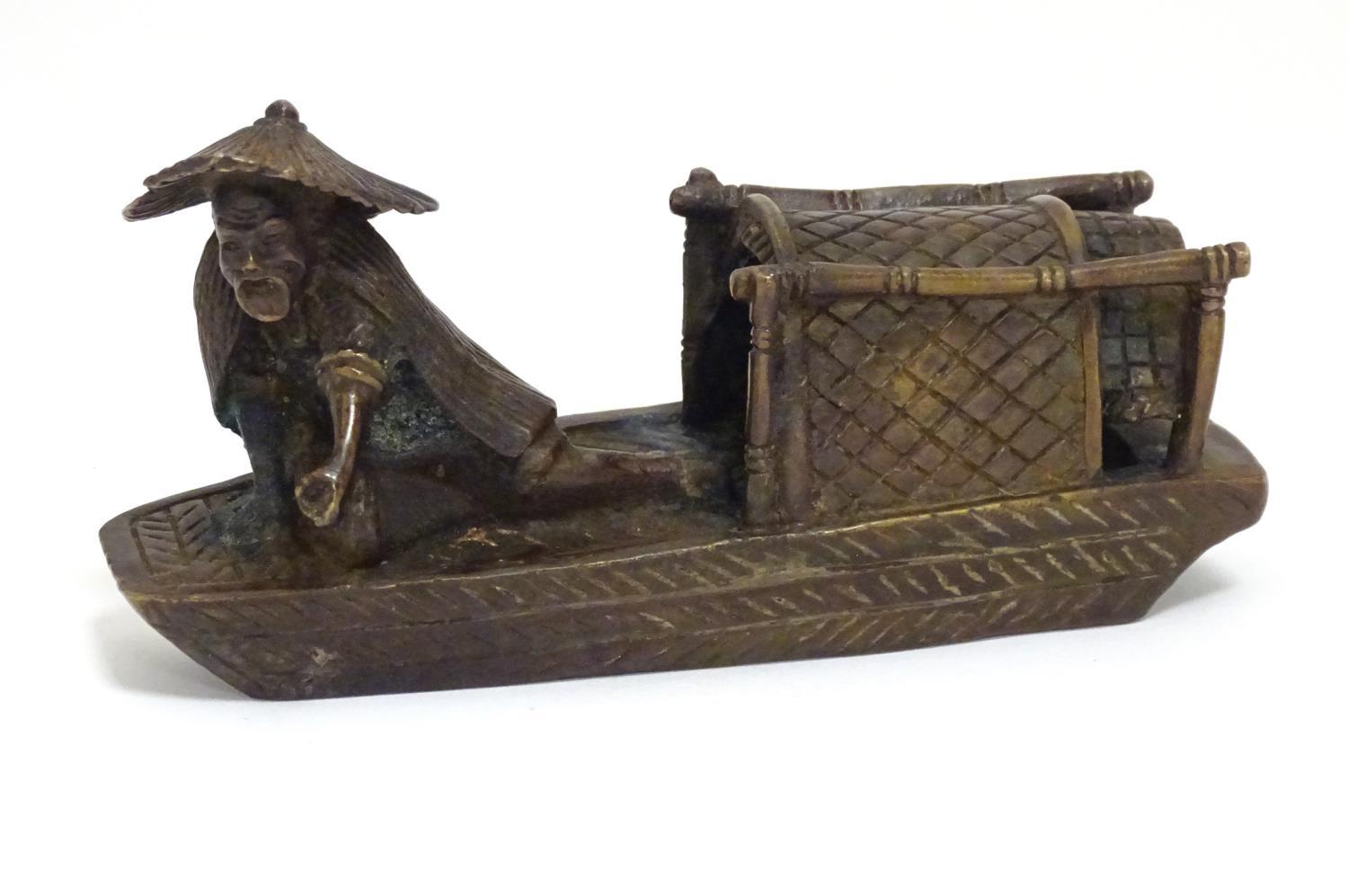 An Oriental bronze model of a fishing boat with a figure fishing. Approx. 6 1/2" long Please