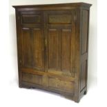 An early 20thC oak wardrobe with a moulded cornice above two doors supported by H-bracket hinges,