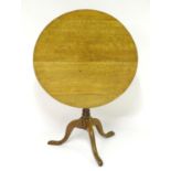A 19thC oak tilt top table with a circular top above a turned pedestal tripod base with three