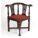 A Georgian carved walnut corner chair, with a carved bowed backrest above three turned incised