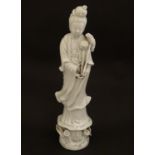 A Chinese blanc de chine figure of Guanyin holding flowers, raised on a base of lotus flowers and