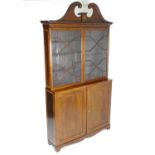 A 19thc mahogany bookcase with a swans neck pediment having moulded roundel decoration and marquetry