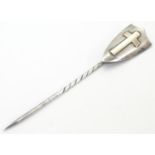 A hallmarked silver stick pin surmounted by a shield cartouche with cross decoration. The whole