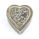 A white metal lidded box of heart form with embossed decoration. 2" long Please Note - we do not