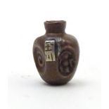 A Japanese ojime bead formed as a stylised vase with impressed detail and applied character mark