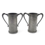 A pair of Arts & Crafts pewter vases of cylindrical form with twin handles and hammered decoration