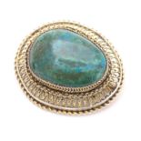 An Oriental brooch with central green / turquoise cabochon within a silver gilt mount. Approx 2"