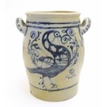 A stoneware crock pot of ovoid form with twin handles and hand painted bird and scrolling foliage