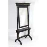 An early 20thC French ebonised cheval mirror, having a moulded cornice above a gilt metal adorned