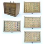 Toys: A wooden box with five drawers containing 144 20thC bamboo Mahjong gaming counters. Box