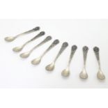 A set of eight Indonesian Yogya silver condiment spoons, each foliate decorated handle terminating