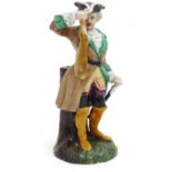 A Continental porcelain figure modelled as a man in a tricorn hat holding dead game / rabbit, on a