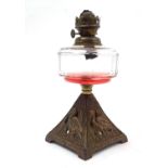 An Arts and Crafts oil lamp with cast bird decoration to the base and having facet cut clear glass