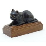 A late 19thC carved horn model of a recumbent cat with etched detail on a wooden base. Approx. 2"