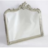 A large painted mirror with a shaped top, carved and moulded floral frame and having a bevelled