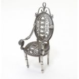 A white metal filigree miniature model of an open arm chair / dolls house chair. Approx 2 1/4"