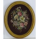 A Victorian oval woolwork embroidery / needlework depicting a floral display with lilies, roses