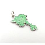 A silver charm formed as the Channel Island Sark and decorated with green guilloche enamel detail.