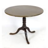 An early 19thC mahogany tripod table with a circular table top above a turned pedestal base and