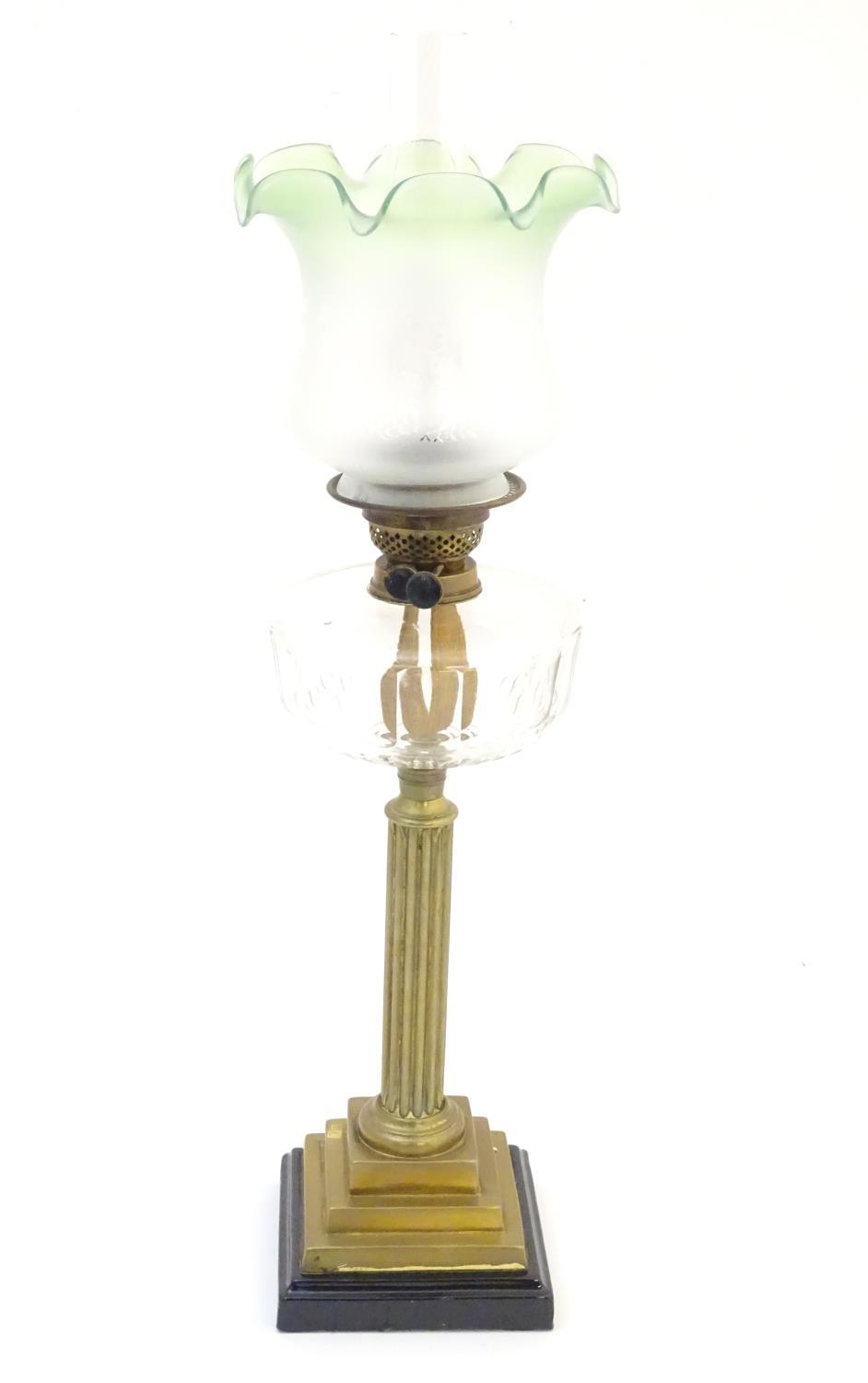 A late 19thC / early 20thC oil lamp, the brass column on stepped base supporting a clear cut glass