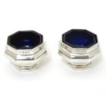 A pair of silver salts of octagonal form with blue glass liners. Hallmarked Birmingham 1922 maker