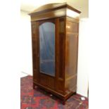 An early 20thC mahogany wardrobe with a bowed pediment above a moulded cornice and decoratively