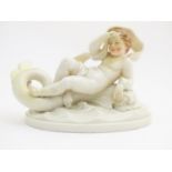 A figurine modelled as a recumbent putto resting on a dolphin in the manner of Royal Worcester.