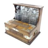A Victorian oak tantalus with carved floral and foliate detail and silver plate mounts. With three