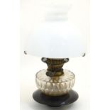 A 19thC oil lamp, the black glass base with facet cut glass reservoir and white milk glass shade.