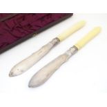 A cased pair of late 19thC silver plated butter knives with carved ivory handles. The blades with