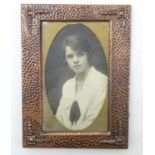 An Arts & Crafts copper photograph frame with hammered decoration and embossed corner detail.