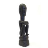 Ethnographic / Native / Tribal: A carved wooden figure depicting a seated man with his arms