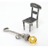 A small dolls house style white metal chair with filigree style decoration. Approx 1" high. Together