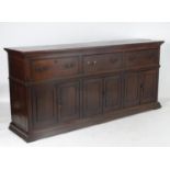 An 18thC oak dresser base with a moulded top above three sets of panelled cupboards below three long