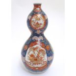 An Oriental double gourd vase in the Imari palette with lobed panels depicting plants on a