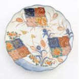 A Japanese plate with a lobed rim, hand painted in the Imari palette with stylised flowers and