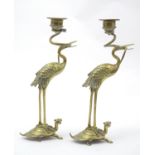 A pair of late 19thC Oriental cast brass candlesticks modelled as a crane bird standing on the