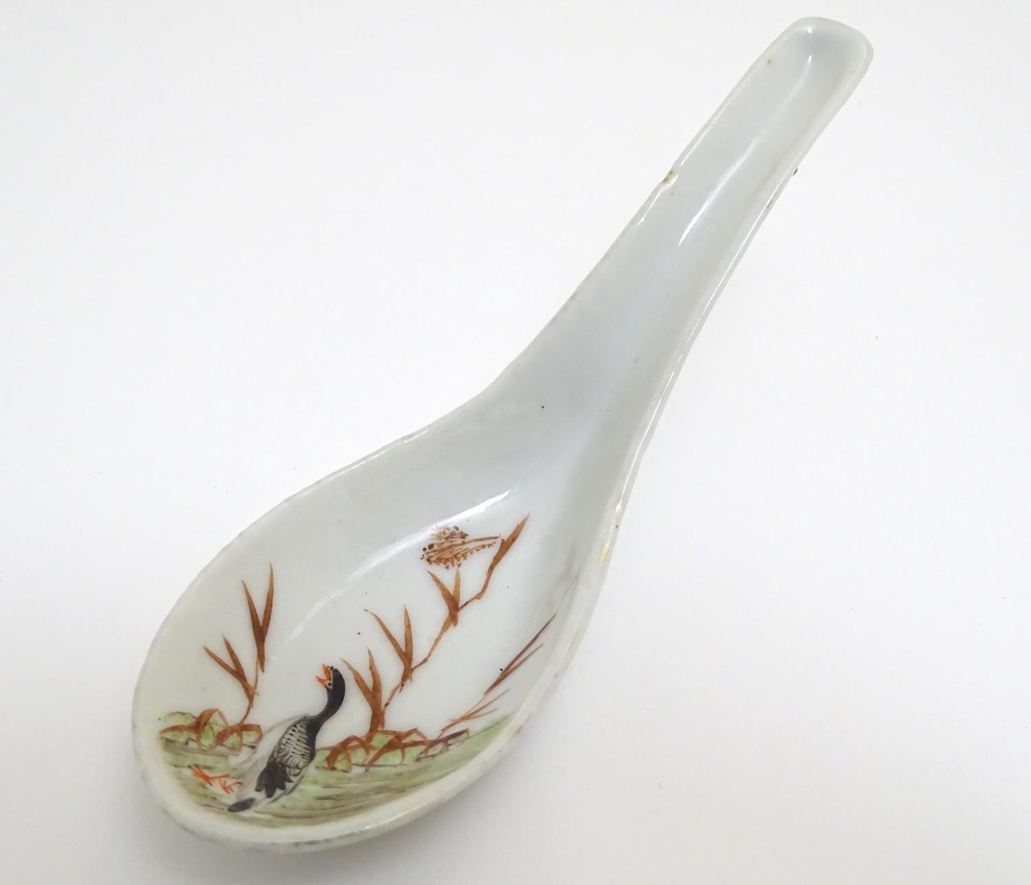 A Chinese rice / soup spoon with hand painted decoration depicting a goose / bird in a wetland