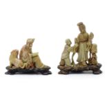 Two Oriental carved soapstone figures, a lady with a fan and child, and a seated scholar with a