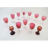 Ten assorted cranberry glass drinking glasses together with two ruby glass drinking glasses with