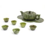 An Oriental carved soapstone small tea set with a lobed teapot, six tea bowls, and a quatreform