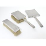 Art Deco silver dressing table items with engine turned decoration. Comprising two brushes and