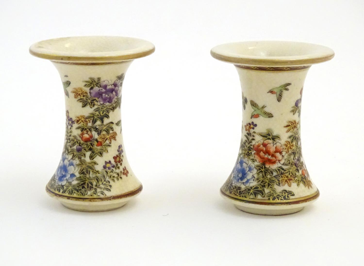 A pair of Japanese miniature Satsuma vases with flared rims and bases, decorated with flowers and