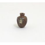 A Japanese ojime bead formed as a stylised vase with impressed detail and applied character mark