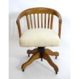 An early 20thC oak library chair with a with a bowed back and slatted supports above and an