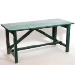 A vintage green painted table with a planked top above four supports united by rectangular