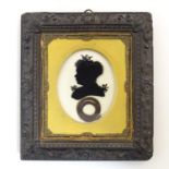A 19thC oval reverse glass silhouette portrait miniature depicting a woman with a bow in her hair