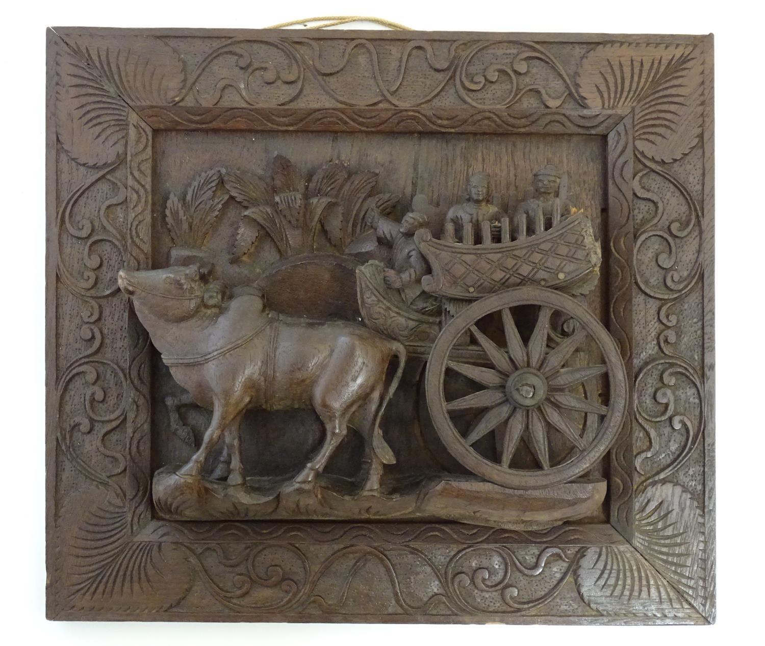 A 20thC Chinese carved wood wall plaque depicting oxon pulling a cart with figures, the border